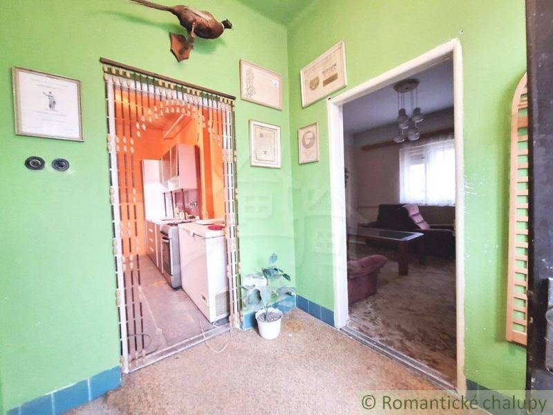 Interior of a room in a family house with wall decorations and entrances to the kitchen.