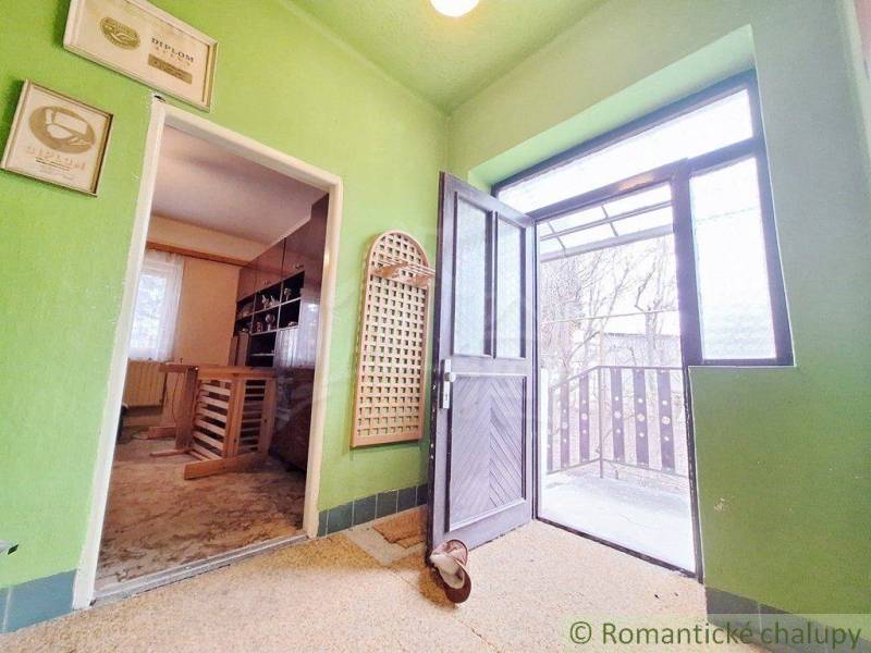 Interior of a family house with open doors to the terrace, green walls, paintings.