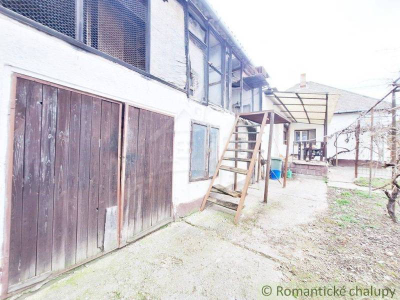 An older family house with wooden doors, an exterior staircase, and courtyards, awaiting renovation.
