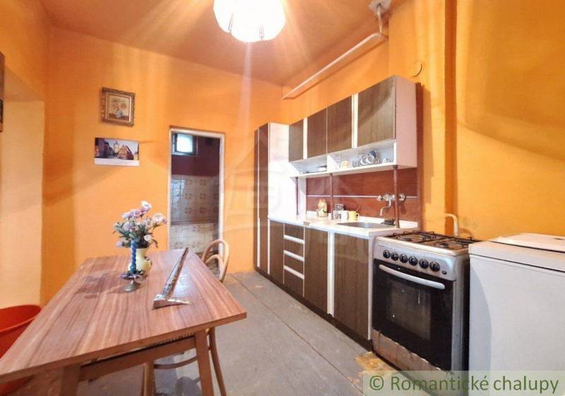 Kitchen with a wooden table, stove, family house; decorations and orange walls.