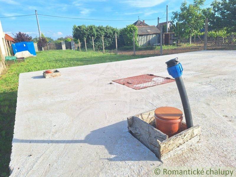 Concrete surface with a pipe and the surrounding garden and rural architecture.