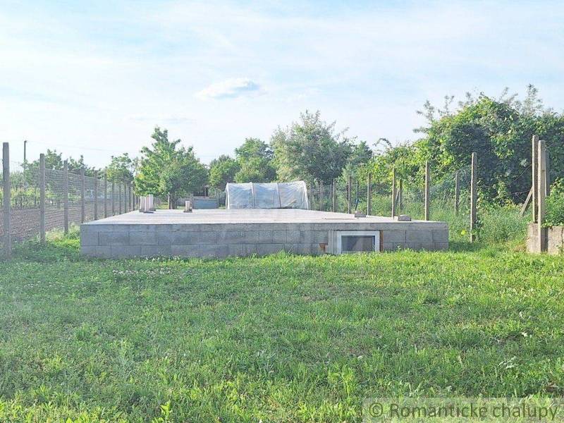 Concrete foundation in the garden, surrounded by lawn and fence. Ideal for building a small house.