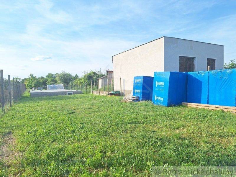 In the picture, there is a garden, stacked building materials, and a building.