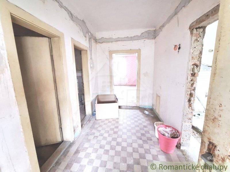 The interior of an unrenovated cottage with worn-out floors and walls, suitable for renovation.