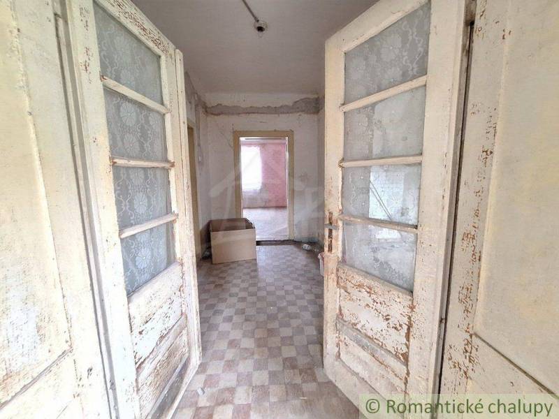 A cottage with vintage doors, tiled floor, a room with a box, plaster peeled off.