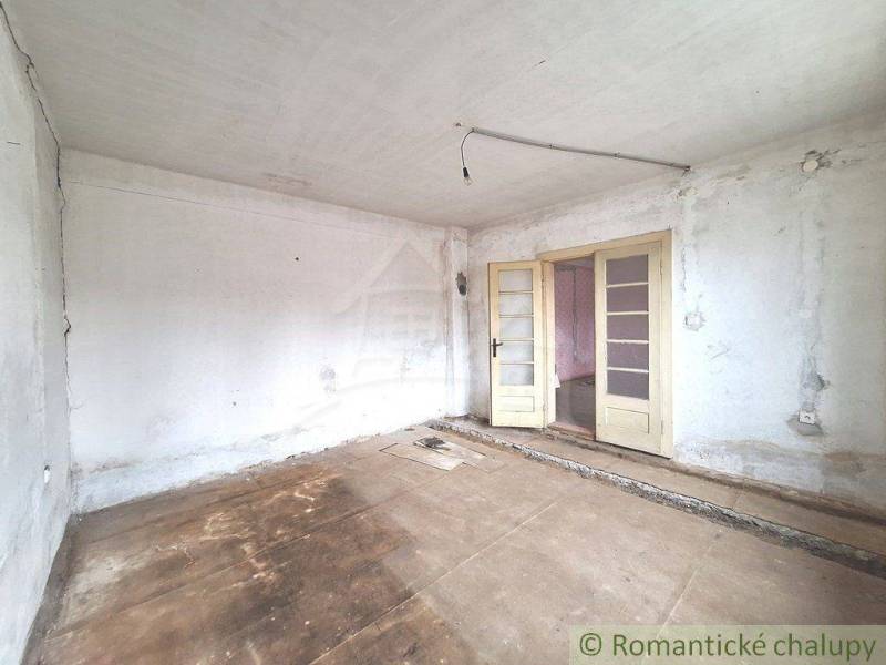 White room with double doors, worn floor, view of entrance to another room, cottage.