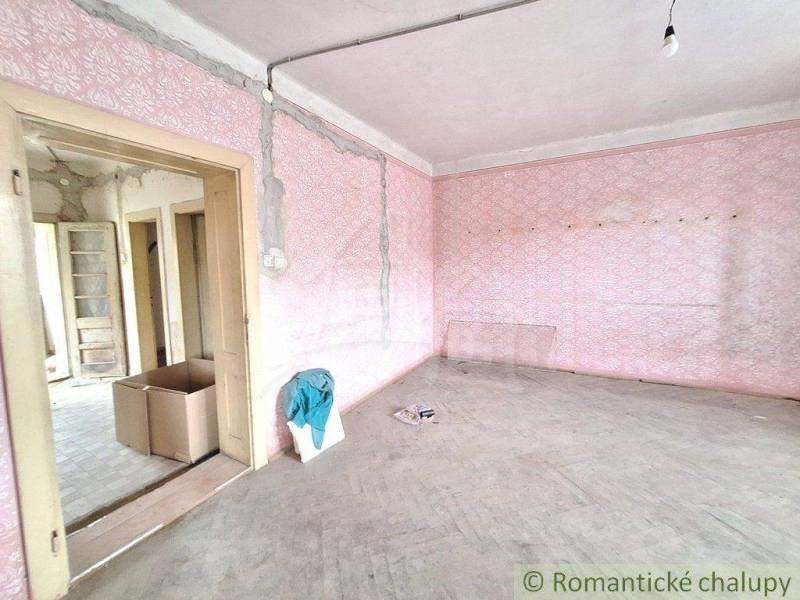 A room with pink walls, wooden floors in a cottage ready for renovation.
