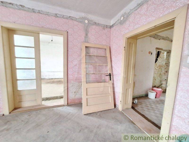 An interior with pink wallpaper and old doors, suggesting the state of cottage renovation.