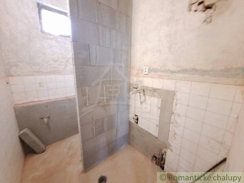 Bathroom under renovation with tiles in a cottage. Original plumbing and sink.