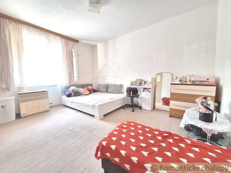 A room in a family house with a bed, a work desk, and pleasant natural lighting.