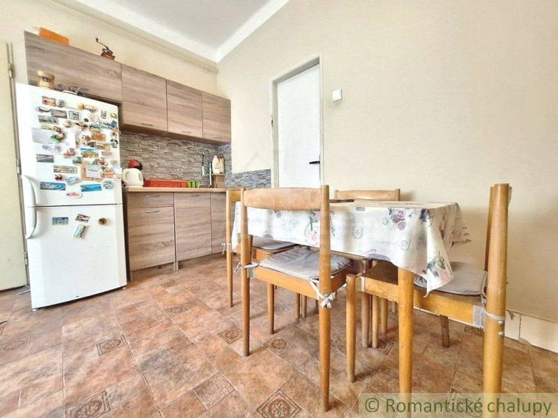 A kitchen with a family house, contains wooden furniture and a refrigerator with magnets.