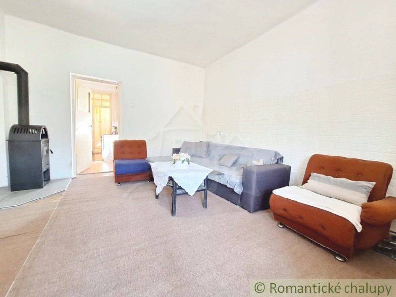 Living room with a stove, sofa, and armchairs in a family house, ideal for family gatherings.