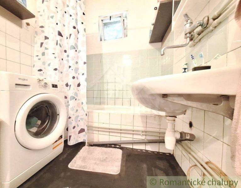 A bathroom in a family house with a bathtub, a washing machine, and a sink, decorative tiles on the wall.
