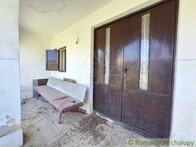 Entrance area of a unique property with a bench and large wooden doors.