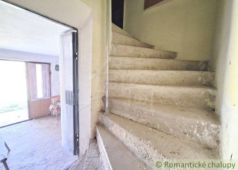 Interior with concrete stairs and a bright room underneath them. Unique real estate.