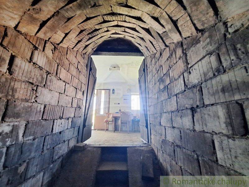 Arched passage in the Peculiar Properties leading to a room with a wooden table and chairs.