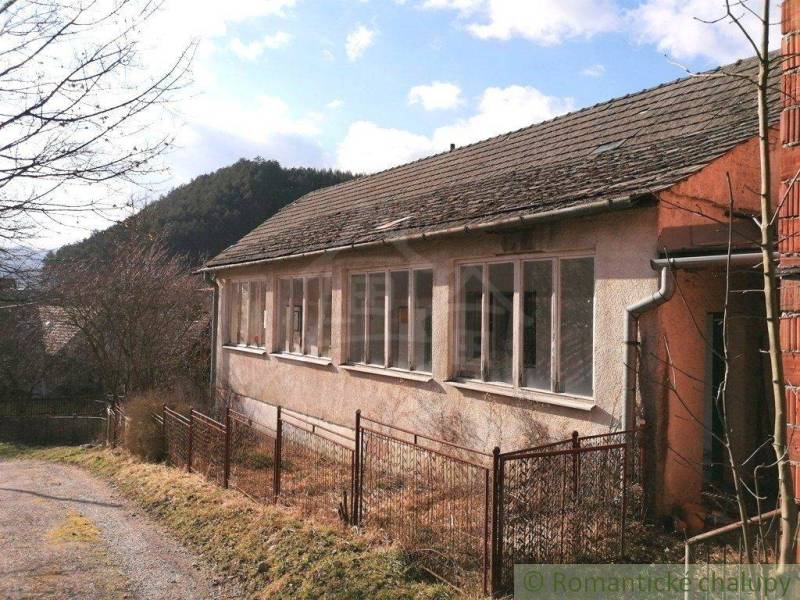 A family house surrounded by nature, fenced on a country road.