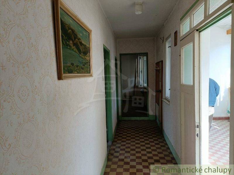 A hallway in a family house with a tiled floor, a painting, and a window for natural light.