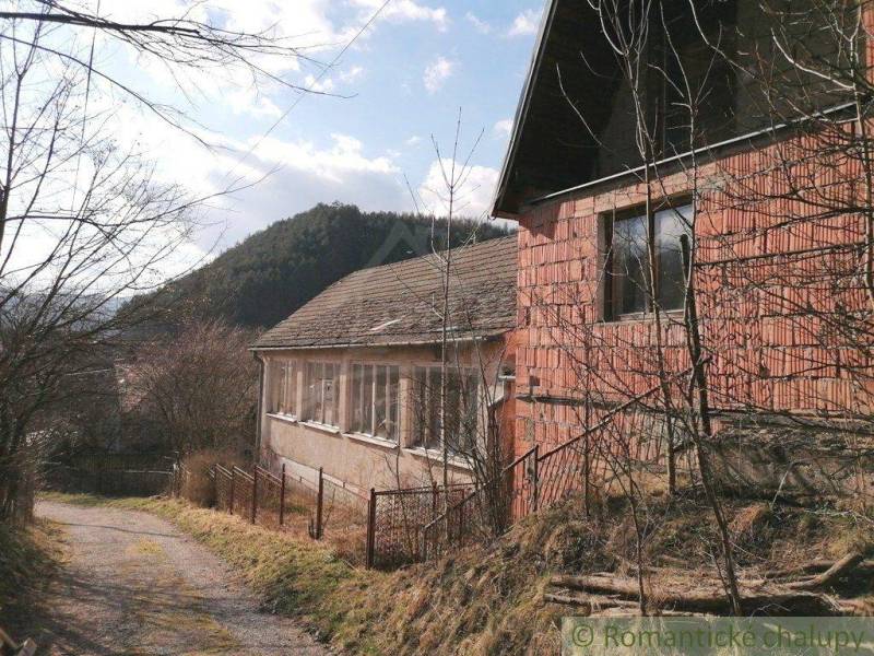 A brick family house, next to it a narrow driveway with a view of the hills.