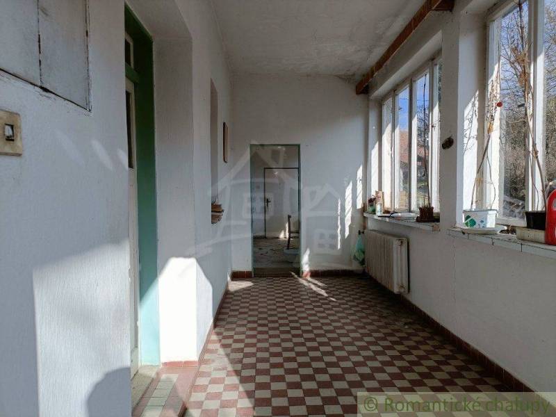 A sunlit porch in a family house with large windows and a tiled floor.