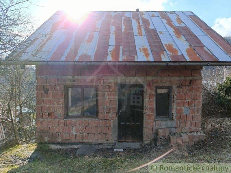 In the picture is an old brick cottage with sunlight shining through the rusty roof.