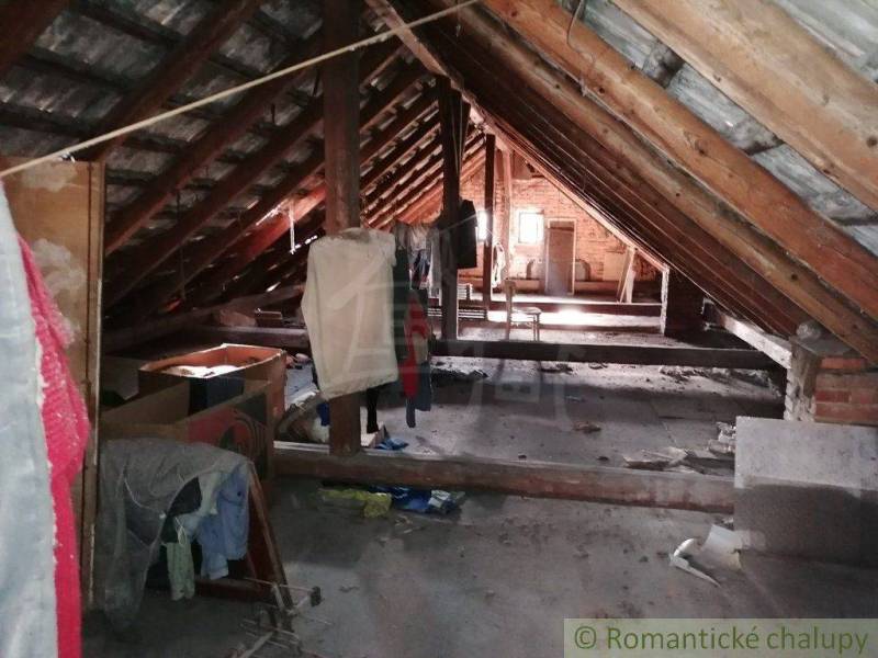 Attic in a rural family house with wooden beams and clutter.