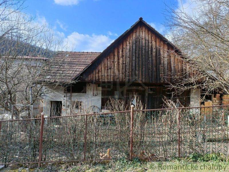 A country house surrounded by trees and a fence, with a blue sky overhead.