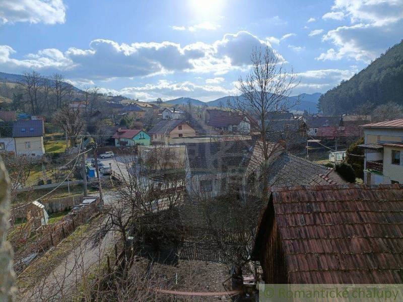 A village surrounded by hills, family houses with a rural atmosphere, and a blue sky.