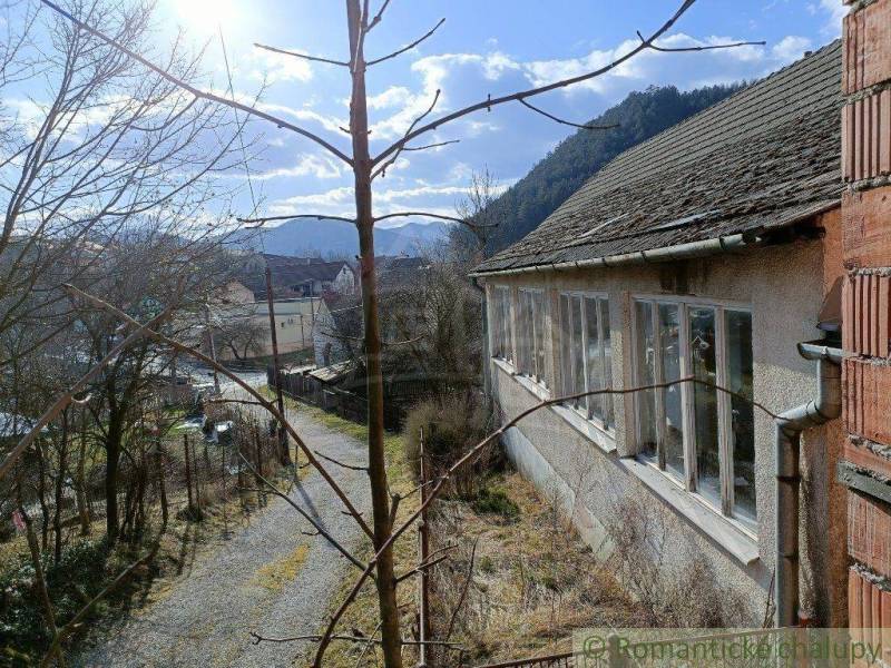 An old building on a sunny slope in a mountain village with a family house.