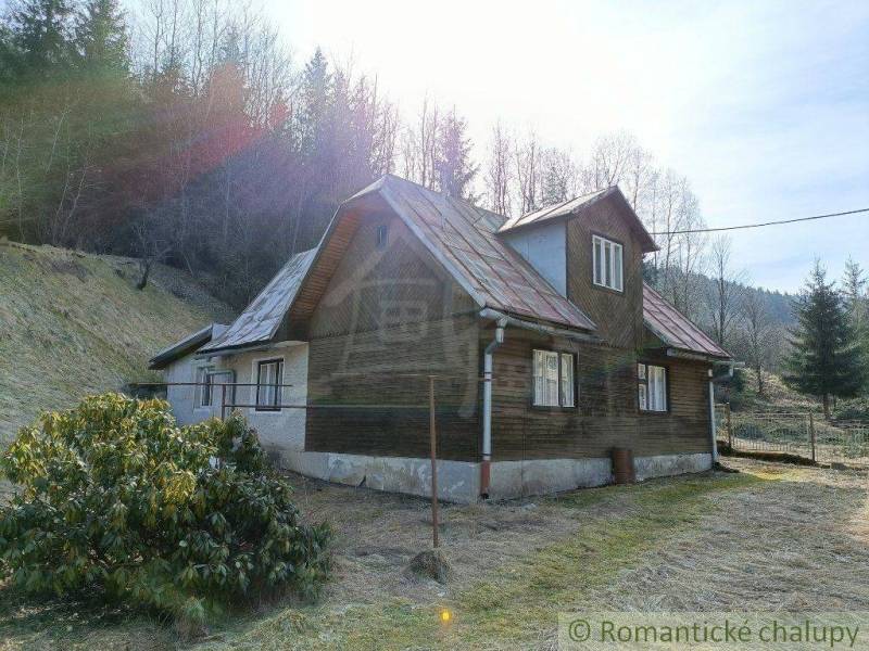 A rustic cottage in a mountainous landscape surrounded by forests, ideal for relaxation in nature.