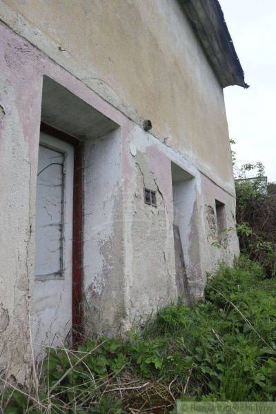 An abandoned family house with cracked walls and an overgrown yard.