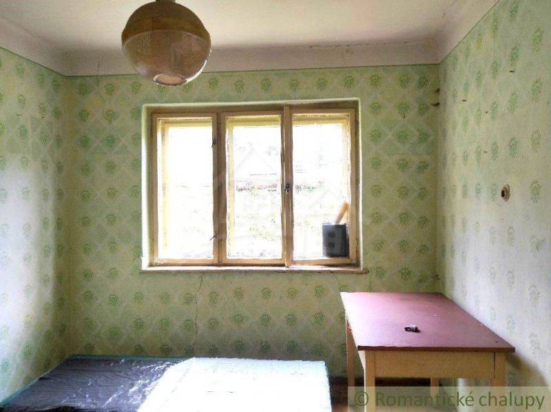 Green wallpaper, a table, and simple lighting characterize the room in the family house.