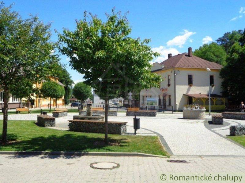 A small square surrounded by trees, benches, and gardens offers a cozy atmosphere for relaxation.