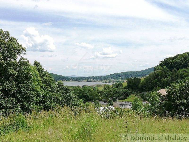 Gardens and natural landscape, overlooking a small village surrounded by mountains and a river.