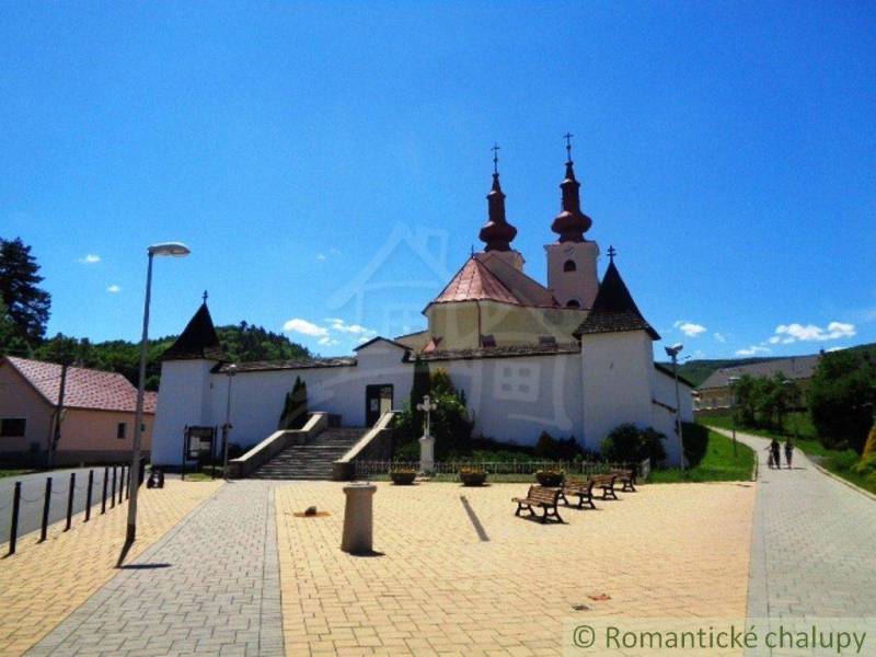 A historic church with two towers surrounded by benches and gardens on a square.