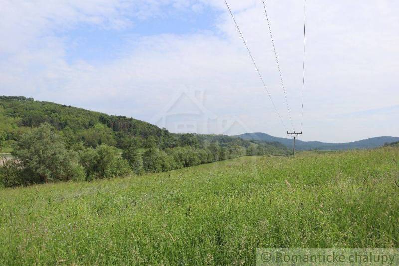 A meadow with power lines, hills on the horizon, a peaceful landscape, an ideal plot for a family house.