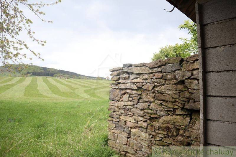 Stone wall, meadow, hills, family house in a natural landscape.