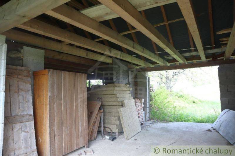 A construction shelter, wooden structure, cabinets, and nature behind the family house.