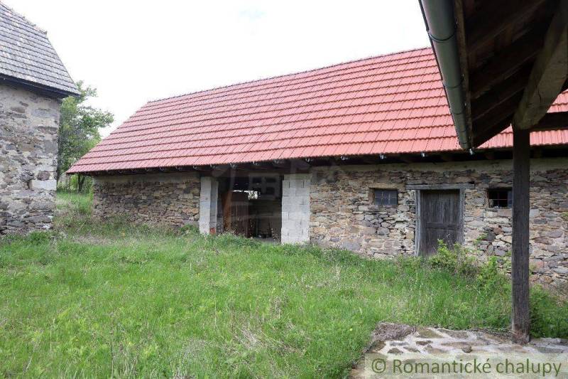 Stone cottage with a red roof on the grass, traditional family house.
