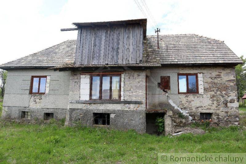 An older rural family house with stone walls and a shingle roof.