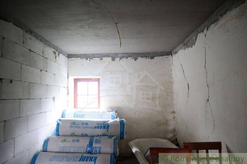 A room in a family house with white walls, bundles of insulation material, and a small window.
