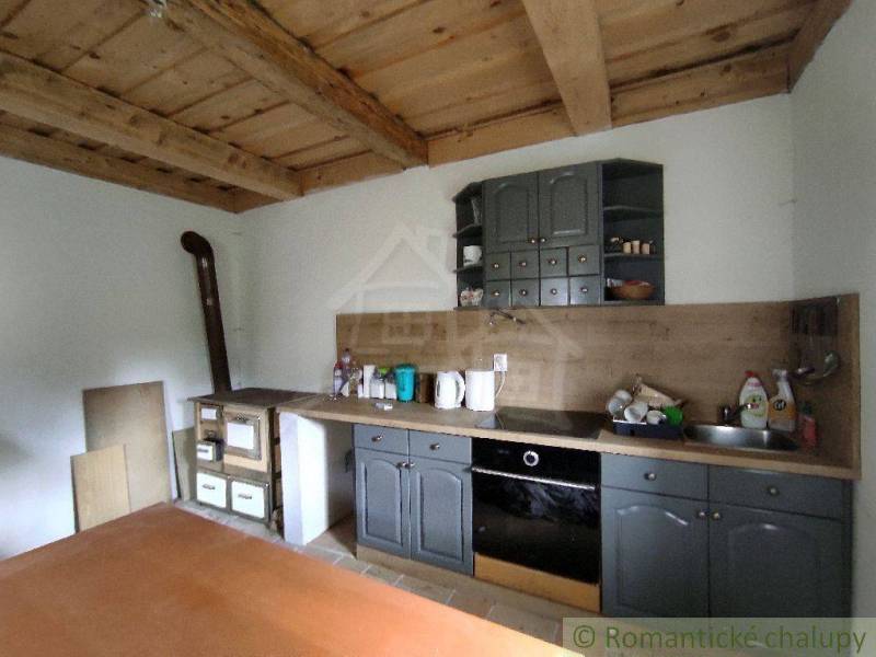 Wooden ceiling in the kitchen with a traditional fireplace and kitchen unit in a family house.