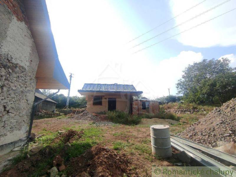 A family house in the countryside, surrounded by building materials and nature.