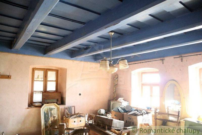 An old interior with a blue wooden ceiling, windows, a swing, and furniture in a family house.