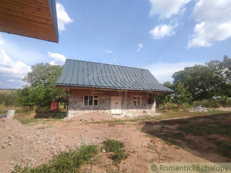 Stone family house with a sloped roof in the middle of a natural environment.
