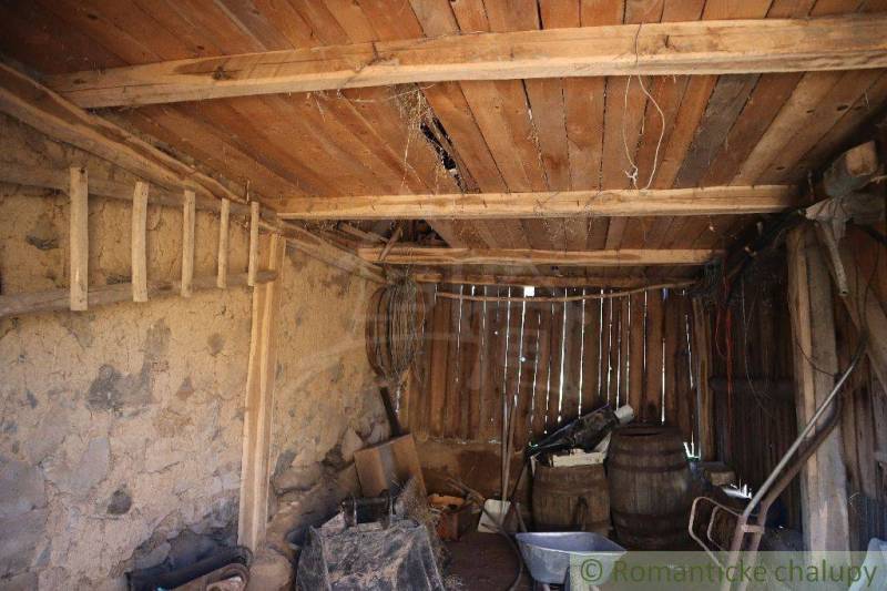 An old wooden barn contains various tools and a family house in the background.
