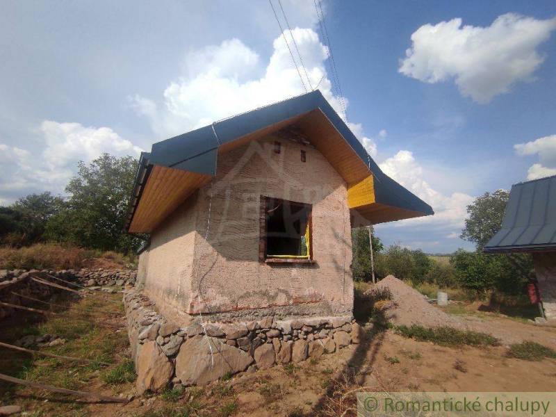A small family house under construction in a natural environment with unfinished walls.