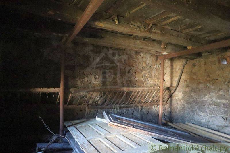 Description of a room in an older family house with stone walls and a wooden ceiling.