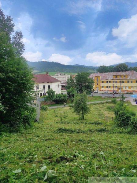 A landscape with a mountain background, buildings, and a green plot for village living.