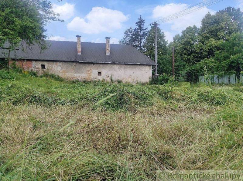 An old house surrounded by grass and trees, ideal for renovation on the property.